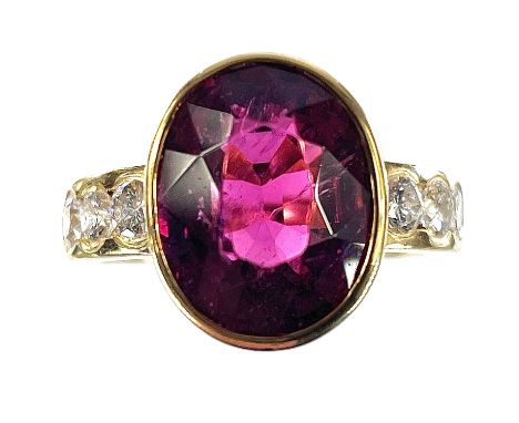 An 18ct gold pink tourmaline and diamond set seven stone dress ring, the oval tourmaline in a collet setting and measuring 6c