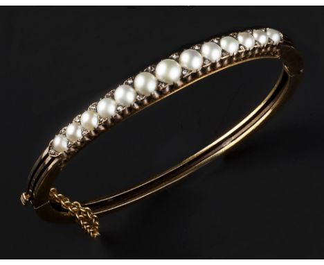 A HALF PEARL AND DIAMOND SET BANGLE, of hinged trifurcated form, set to the front with a panel of graduated half pearls, spac
