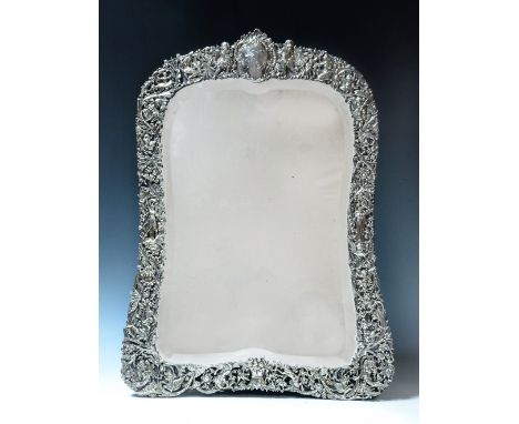 A LARGE VICTORIAN SILVER MOUNTED EASEL FRAMED TABLE MIRROR, pierced and chased with mythical, classical and cherub figures by