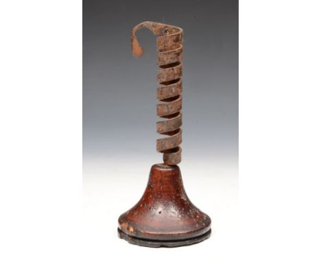 A 17TH CENTURY IRON AND WOODEN CANDLESTICK of wrythen form on a tapering base, 22cm high