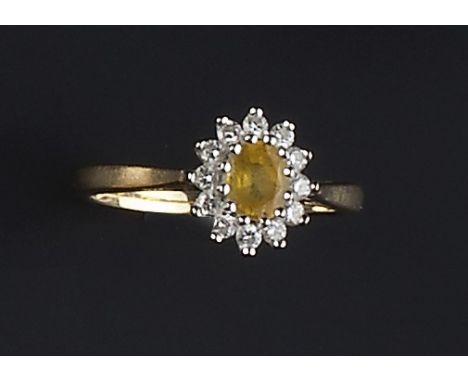 A DIAMOND AND YELLOW SAPPHIRE CLUSTER RING, the oval mixed-cut sapphire claw set within a frame of brilliant-cut diamonds, 18