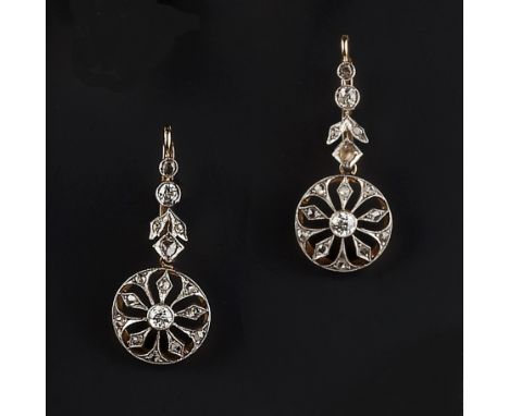 A PAIR OF DIAMOND SET EAR PENDANTS, each pierced circular drop suspended from a foliate surmount, millegrain set with old, br