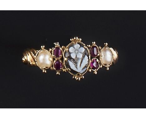 A VICTORIAN GEM SET MEMORIAL RING, centred with a floral carved agate panel, between pairs of oval-cut rubies and half pearls