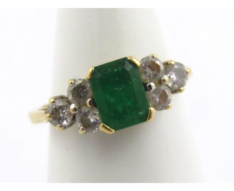 An 18ct gold emerald and diamond dress ring, set with central square cut emerald, flanked by two sets of three tiny diamonds,