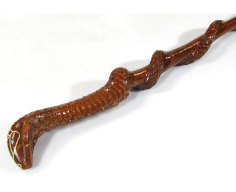 A heavily carved cobra wooden walking stick, with entwined stem and metal tip end, 99cm wide.