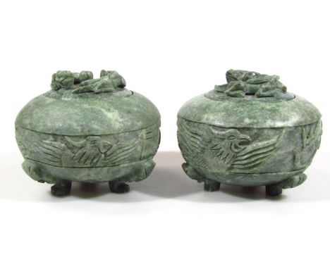 Two polished jade coloured pots, of compressed circular form, with flush lids, each with dragon and orb knops and a bellied c