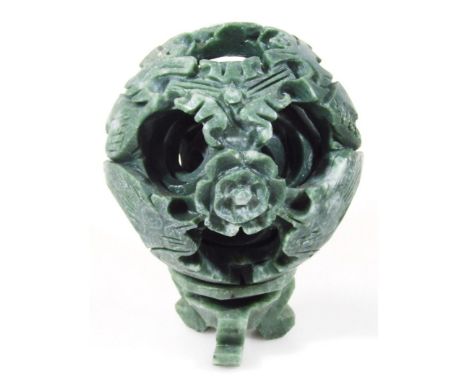 A polished stone jade coloured puzzle ball, with at least four sections, heavily carved on a removable base terminating in in