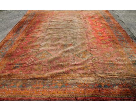 A Turkish carpet, decorated with a geometric floral pattern on red ground.(381cm x 306cm)