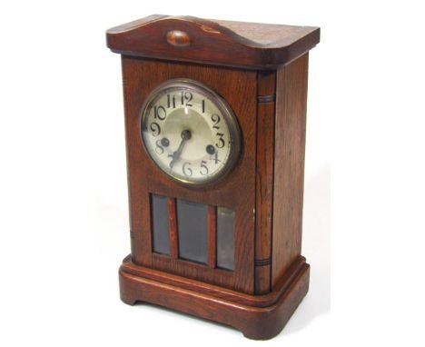 An early 20thC oak mantel clock, the 12cm dia. Arabic dial revealing an eight day movement in a carved case, 36cm high.