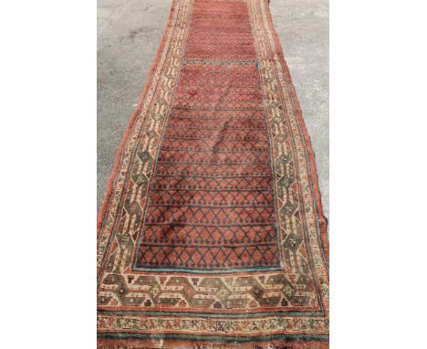 An Asian carpet runner, with a repeat geometric floral pattern predominantly in cream, brown, blue and red. (355cm x 100cm)