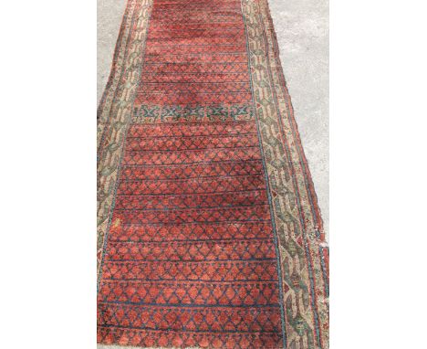 An Asian carpet runner, centred by a repeat geometric 'X' decoration, with outer geometric banding predominantly in red and b