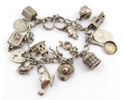 A charm bracelet, with heavy links and heart shaped clasp, set with a number of charms, to include oil lamp 4.5cm high, etc.,