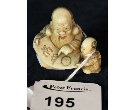 Japanese carved ivory Netsuke as a seated Immortal with scroll and small child.