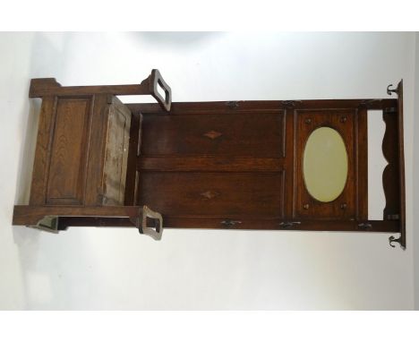 An oak hall stand with oval mirror to the back, flanked by coat hooks and the seat opening flanked by stick stands, 186cm hig