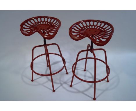 A pair of red painted cast iron adjustable tractor seat stools