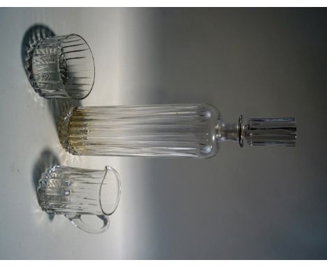 A tall glass decanter and stopper, cut with a vertical linear design, with matching milk jug and sugar bowl