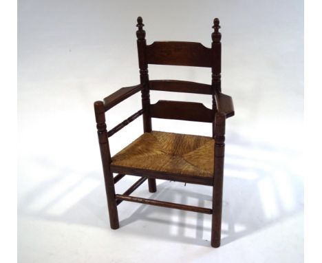 An oak and rush seat seated armchair, with ladder back, turned supports and wide arm rests, 98cm high x 62cm wide