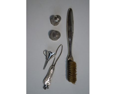 A silver and enamel small brush; a silver thimble; another thimble; a silver perfume bottle funnel; and a sewing item
