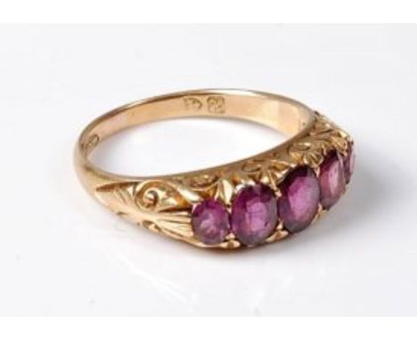 An early 20th century 18ct five stone amethyst ring, the five graduated amethysts with scrolled gallery and shoulders taperin