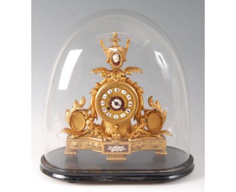 A Victorian gilt metal mantel clock under glass dome, the clock surmounted with a neo-classical pedestal urn, the dial with p