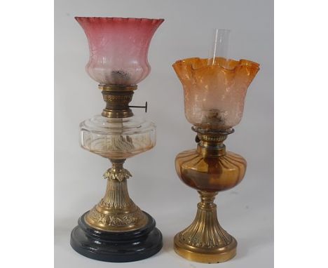 A Victorian brass pedestal oil lamp, having red tinted acid etched waisted shade, slab-cut glass font, and on black enamel pl