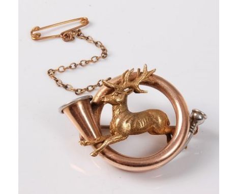 A stag and bugle hunting brooch, the naturalistically modelled stag leaping through a hunting bugle, in tri-coloured metal (m