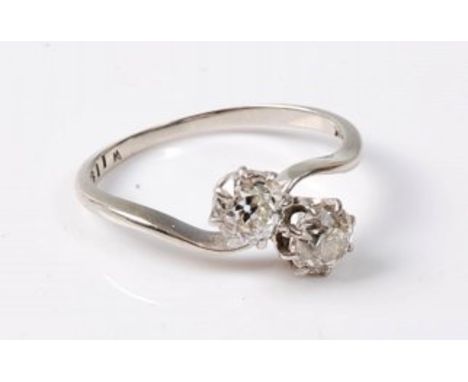 An 18ct two stone 'toi et moi' diamond ring, the two old cut diamonds, total estimated approx. 0.84cts, in a crossover style 