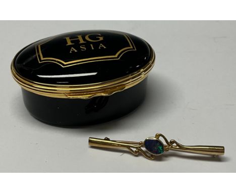 A 9ct gold bar brooch, set with a polished oval fire opal cabochon, 4.5cm, 2g; a Halcyon Days oval enamel trinket box (2) 