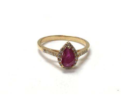 A gold ring set with a drop shape ruby surrounded by small diamonds. The approximate ring size is N.