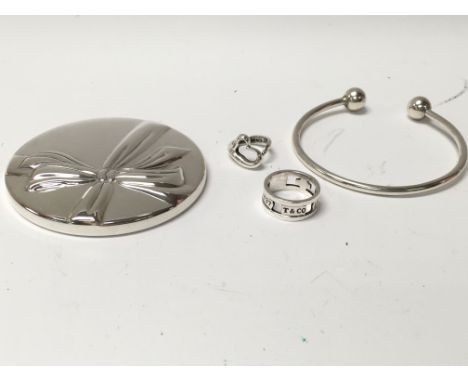 A Tiffany and Co silver bangle with unscrewing end for charm attachments. Also two silver Tiffany rings and a Tiffany silver 