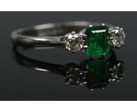 An Art Deco 18ct gold and platinum emerald and diamond three stone ring. Size O. 2.46g.  Small chips to central emerald. Spli