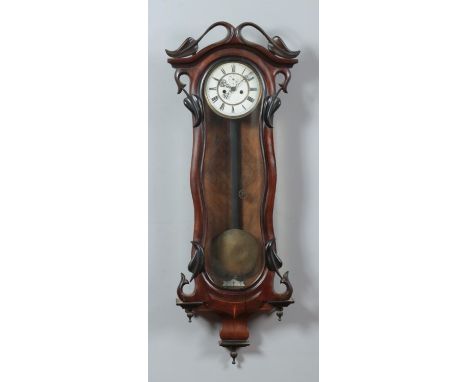 An Art Nouveau mahogany cased Vienna wall clock. Having carved leaf decoration. Length 108cm, Width 40cm.  Feather damaged, w