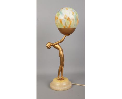 An Art Deco style bronzed figural table lamp depicting a woman with outstretched arms holding a spherical shade. Raised on st