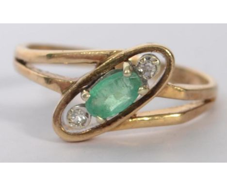 A hallmarked 9ct gold ring set with an oval cut emerald flanked by two bezel set diamonds in the Art Deco style. Hallmarked f