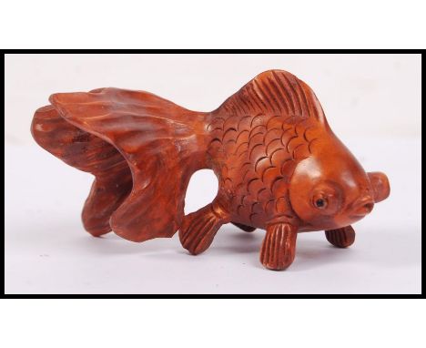 An oriental carved wooden netsuke in the form of a carp fish with large bulging eyes.