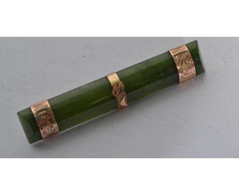 A 9ct gold and jade bar brooch having thee gold bands with pin to verso.