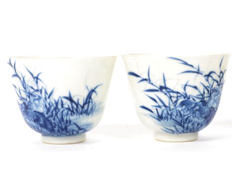 A pair of early 20th century Oriental Chinese ceramic blue and white tea cups painted with birds and foliage with blue charac