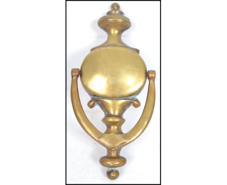 An early 20th century large brass door knocker of oval form with shaped finial top and swag drop, the curved handle having a 