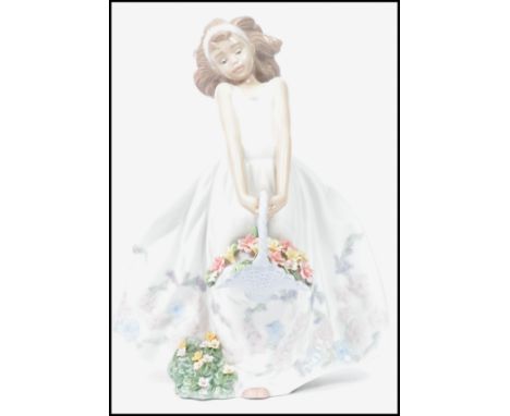 A Lladro ceramic figurine of a girl in dress holding a flower basket with floral bush to base. Impressed marks to base 6647. 