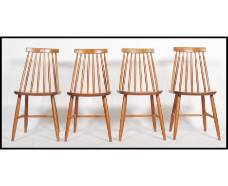 A set of 4 retro 20th century Ercol style stick back dining chairs with saddle seats raised on turned legs united by stretche