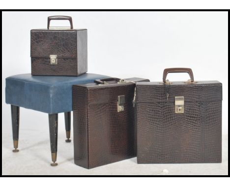 A group of vintage 20th century retro vinyl record cases having a crocodile skin effect look along with a retro stool raised 