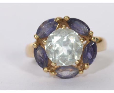 A 9ct gold dress ring set with a central pale blue stone surrounded by oval cut purple stones. Marked 9ct tests 9ct gold. Tot