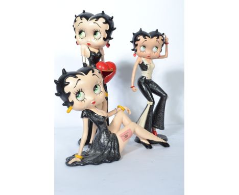 A Betty Boop art deco style figurine of the iconic character in a black evening dress modelled in an seated position.  Along 