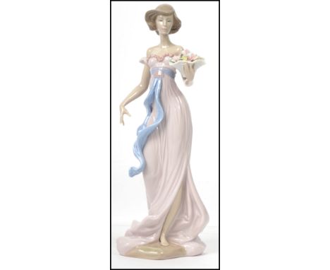 A Lladro ceramic figure of a young lady holding a basket of flowers - the base with impressed No.6365. Measures:  30cm high x