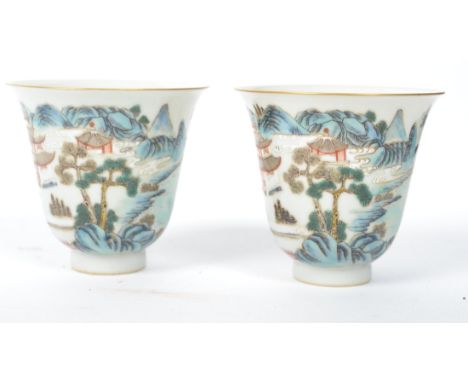 A pair of 19th century Oriental Chinese ceramic tea cups of bell form painted with a landscape scene of mountains and temples