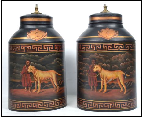 A pair of large decorative tea tins converted to lamp bases with painted decoration of man and dog bearing inscription for Ba