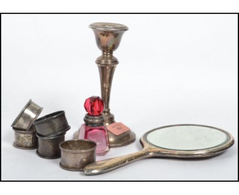 A collection of silver items to include a cranberry glass silver collared scent bottle, napkin rings, candle stick and a hand