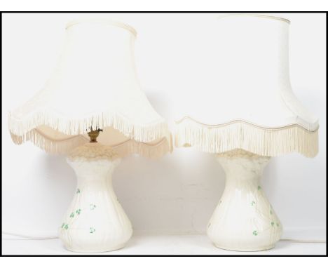 A pair of Irish 20th century Belleek ceramic table lamps decorated in the shamrock pattern, complete with shades. Measures: 5
