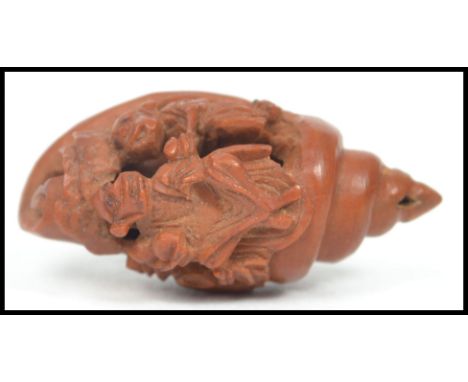 An Oriental miniature carved wooden netsuke in the form of a cornucopia nautical shell depicting two monkeys. Measures 3 cm l