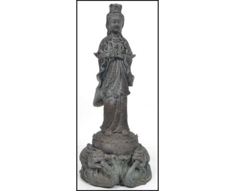 A large Oriental Chinese bronze statue of a Buddha holding a water bottle raised on a floral base surrounded by dragons. Meas